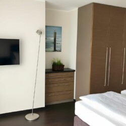 Apartment Morgensonne 4 – Helles Schlafzimmer mit Kleiderschrank und TV für komfortables Langzeitwohnen
